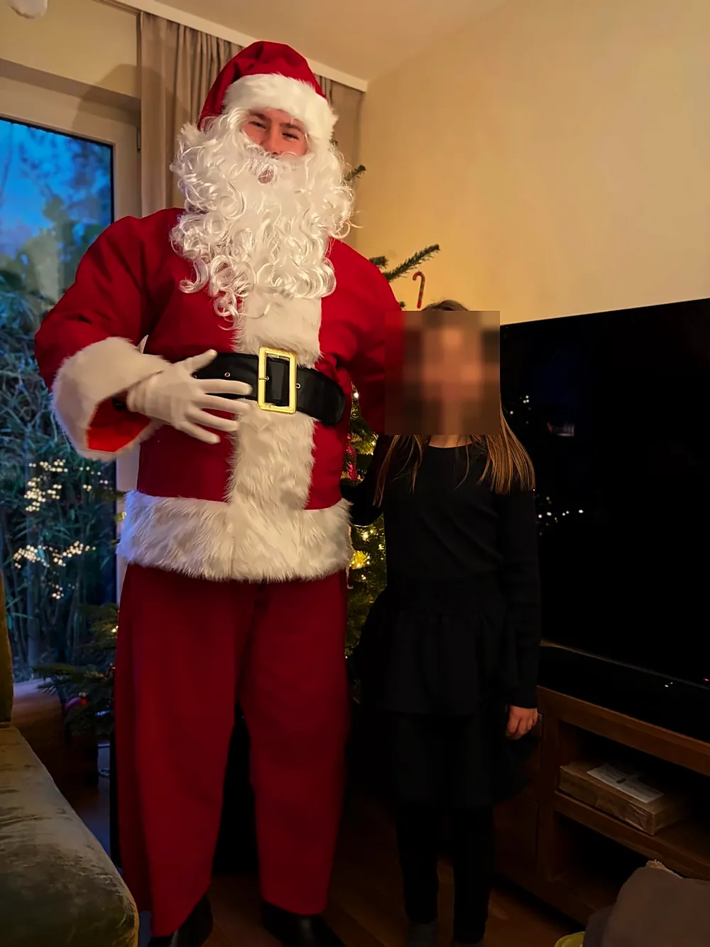 Der Weihnachtsmann mit einem Mädchen vor dem Tannenbaum, Gesicht unkenntlich gemacht